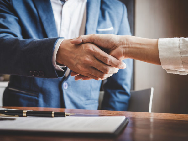 Real estate agent and customers shaking hands together celebrating finished contract after about home insurance and investment loan, handshake and successful deal.